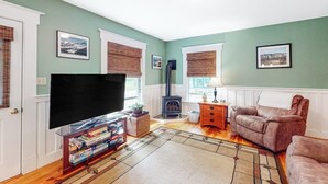 Een woonkamer met een televisie, open haard, bank en vloerkleed.