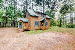 A two-story wooden cabin with a porch, surrounded by a forest. - Sheridans' Getaway | Dog-friendly house in Newry, 1 mile to Sunday River (Newry)
