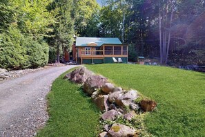 A cabin with a green roof, surrounded by a well-maintained lawn and a gravel path leading to it. - Charming Lakeview House with Deck, Cozy Fireplace and firepit (Rome)