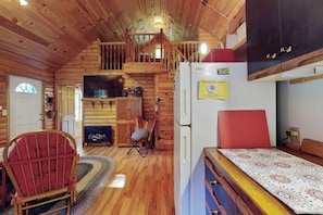 A log cabin interior with a dining area, a kitchen with a refrigerator, and a fireplace. - Charming Lakeview House with Deck, Cozy Fireplace and firepit (Rome)