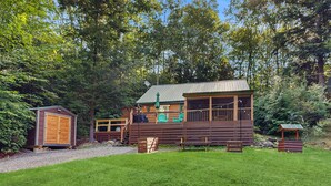 A cabin with a deck, a small shed, and a picnic table in a wooded area. - Charming Lakeview House with Deck, Cozy Fireplace and firepit (Rome)