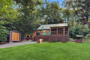A cabin with a deck, a small shed, and a picnic table in a wooded area. - Charming Lakeview House with Deck, Cozy Fireplace and firepit (Rome)