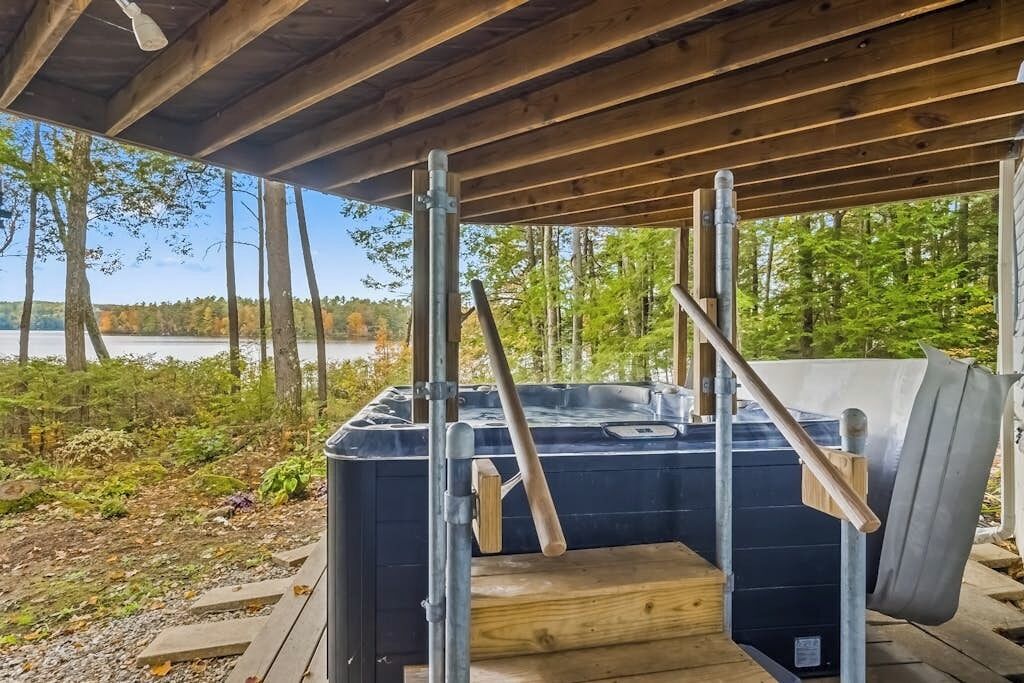 Boblebad under en træterrasse med udsigt over en sø og træer.