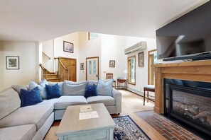 A living room with a sofa, coffee table, fireplace, and a TV mounted on the wall. - Waterfront, dog-friendly home on 12+ acres with dock, hot tub & sunset views (Poland)