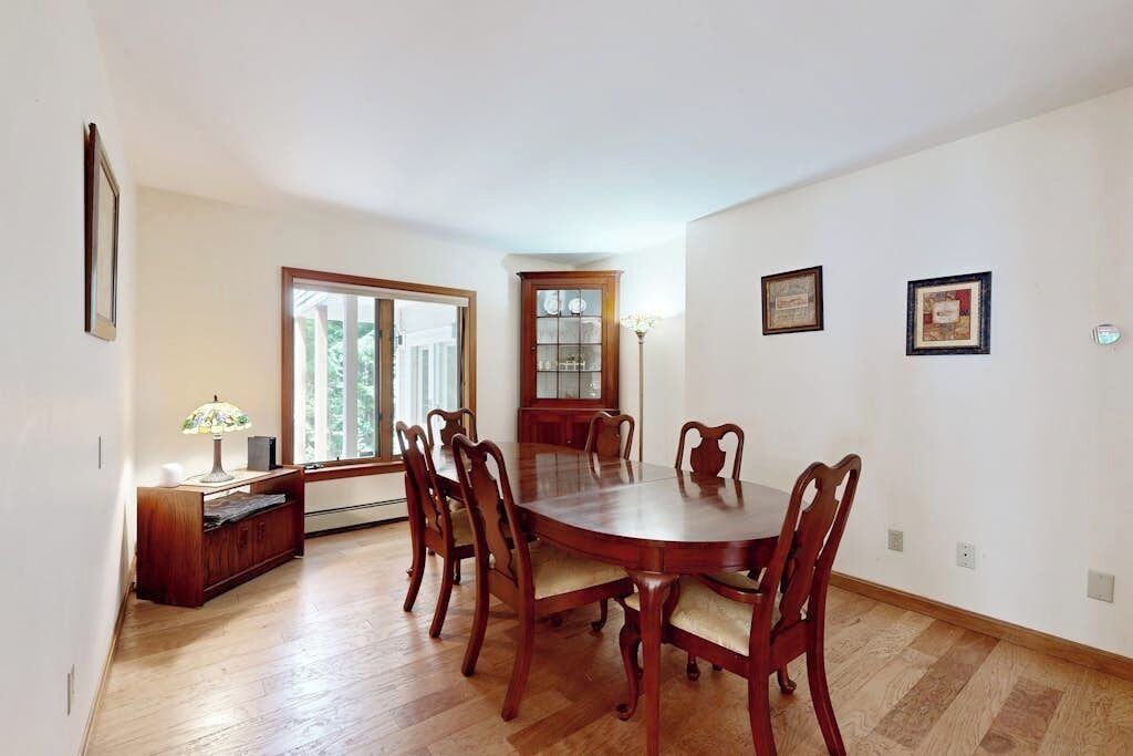 A dining room with a wooden table and chairs, a cabinet, and a window with blinds.