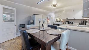 Een moderne keuken met witte kastjes, een eettafel met placemats, en een geïntegreerd kookeiland met een spoelbak.