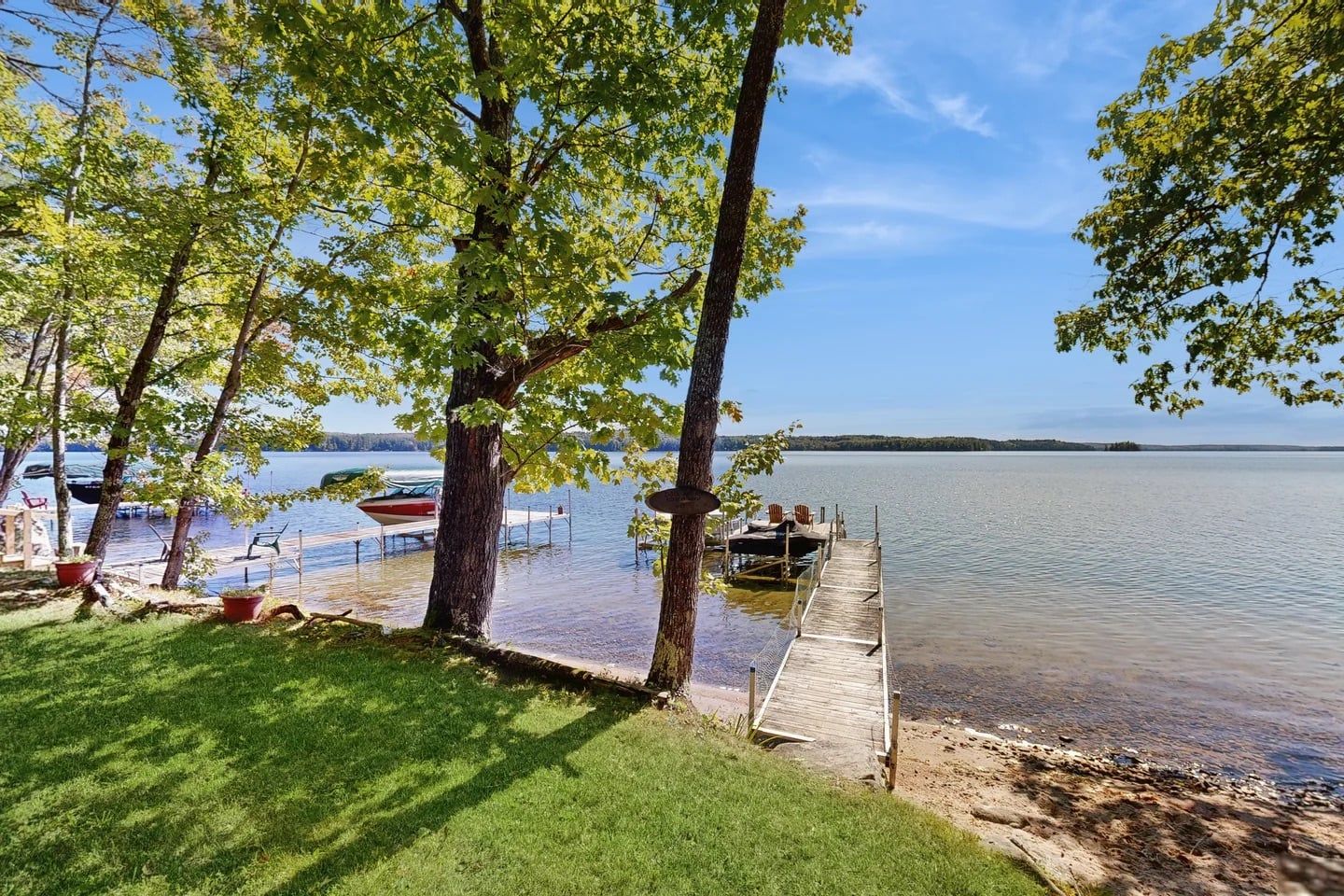 A lakeside dock with boats, a grassy area, and trees.
