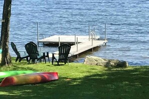 Eine Anlegestelle mit Stühlen und einem Kajak am Wasser.