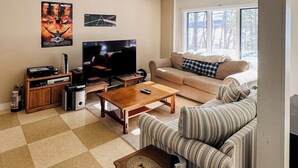 Ein Wohnzimmer mit Fernseher, Sofa, Couchtisch und einem Fenster mit Blick.