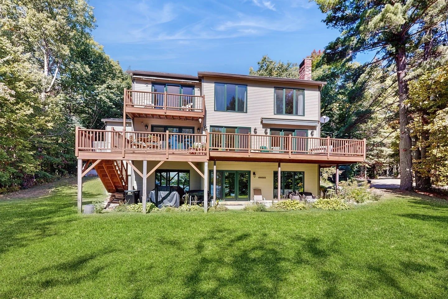 Ein zweistöckiges Haus mit einer Terrasse, einer überdachten Veranda und einer Garage.