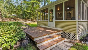 A house with a porch, a small deck, and a wooden staircase leading to the door.