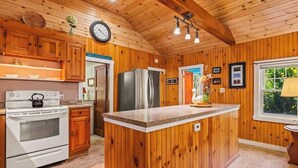 A wooden interior with a kitchen area, including a stove, refrigerator, and wooden cabinets.