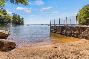 Ein Strand mit einer Steinmauer, klarem Wasser und Booten.