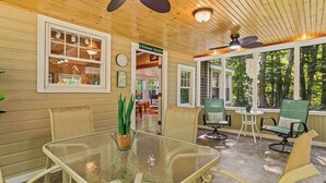 A covered patio with a glass table, chairs, and a potted plant.