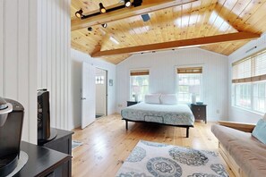 A bedroom with a bed, a television, a wooden ceiling, and large windows. - Charming home with patio & studio - walk to Footbridge Beach (Ogunquit)