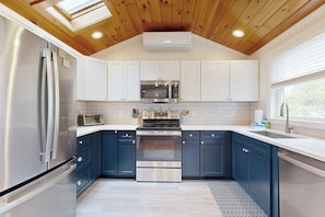 A modern kitchen with a wooden ceiling, stainless steel appliances, and blue cabinets. - Charming home with patio & studio - walk to Footbridge Beach (Ogunquit)
