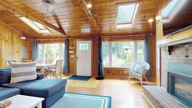 Interior de uma cabana de madeira com sofá, mesa de jantar e lareira.