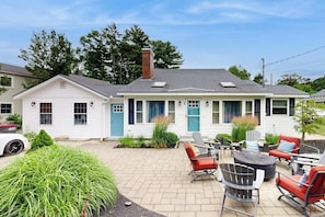 A two-story house with a patio area featuring outdoor furniture and a fire pit. - Charming home with patio & studio - walk to Footbridge Beach (Ogunquit)