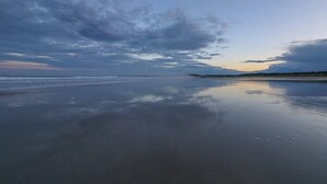 Uma praia com mar calmo e céu nublado.
