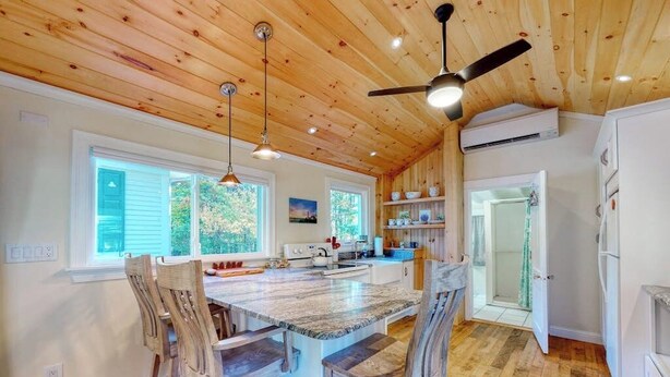 A spacious kitchen with a large island, wooden ceiling, and built-in cabinetry.