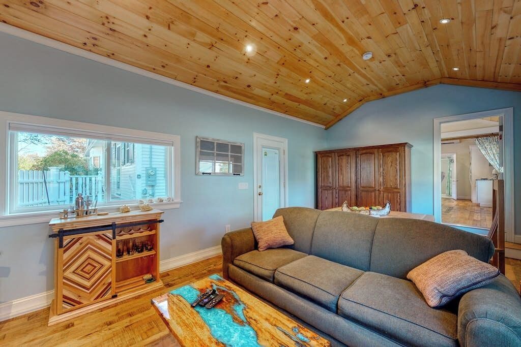 Una sala de estar con techo de madera, un sofá, una mesa de centro y un mueble de madera.