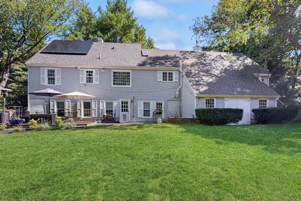 A two-story house with a covered patio, a solar panel on the roof, and a well-maintained lawn.