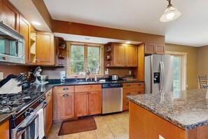 A modern kitchen with wooden cabinets, stainless steel appliances, and a granite countertop.