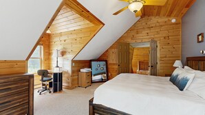 Una camera da letto con soffitto a falde, un letto, una scrivania, una sedia e un armadio.