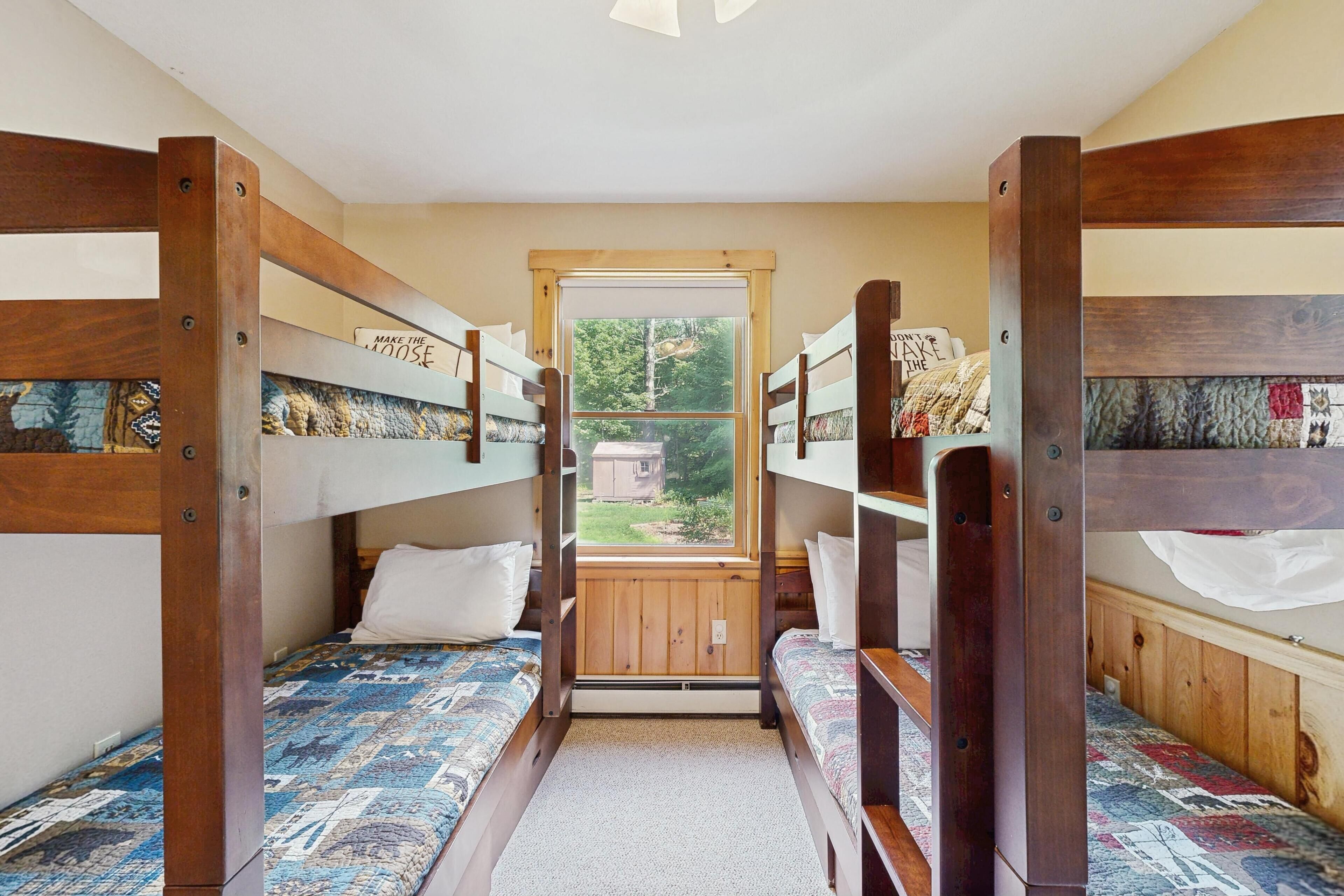 Une chambre avec des lits superposés et une fenêtre donnant sur une forêt.