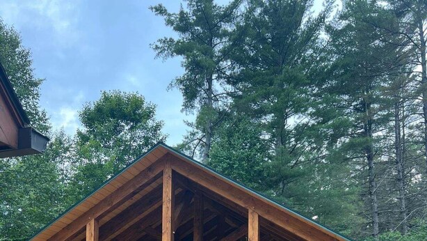Un pontile in legno con tavoli da picnic e un padiglione coperto in una zona boschiva.