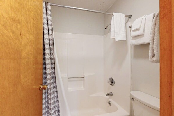 A bathroom with a shower, toilet, and towel rack.