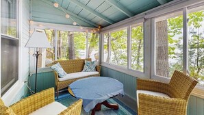 Eine überdachte Veranda mit Korbmöbeln, einem Tisch und Lichterketten.