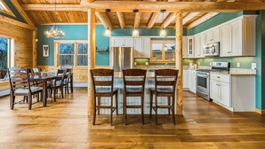 A wooden interior with a dining area, kitchen, and large windows.