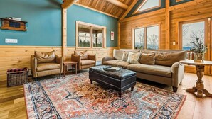 A cozy room with a wooden ceiling, a blue wall, a sofa, a coffee table, and a patterned rug.