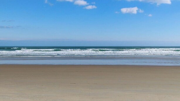 Une plage avec un ciel dégagé et des vagues sur l’océan.