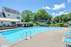 A swimming pool with a covered area, lounge chairs, and a house with a white exterior.