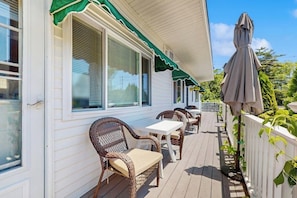 A covered porch with wicker furniture, a white fence, and a green awning.