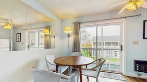 Una habitación con una mesa de comedor, sillas, un espejo grande, un ventilador de techo y vistas a un balcón.