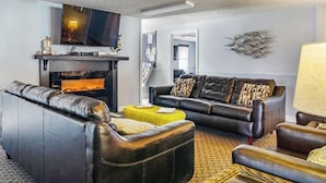 Una sala de estar con sofás de cuero, un televisor de pantalla plana, una chimenea y un elemento decorativo en la pared.