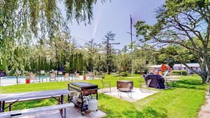 Un patio trasero con una parrilla, una mesa de picnic y una piscina.