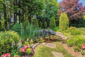 Ein Garten mit Teich, Steinbrücke und unterschiedlichen Pflanzen.
