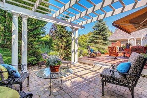 Eine überdachte Terrasse mit einer Pergola, Gartenmöbeln und Blick auf einen Garten.