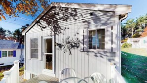 Una piccola casa a un piano con un portico e un tavolo in vetro.