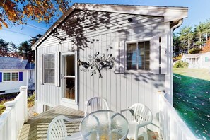 Ein kleines, eingeschossiges Haus mit Veranda und einem Glastisch.
