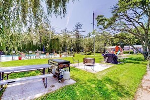 A backyard with a barbecue grill, picnic table, and a swimming pool.