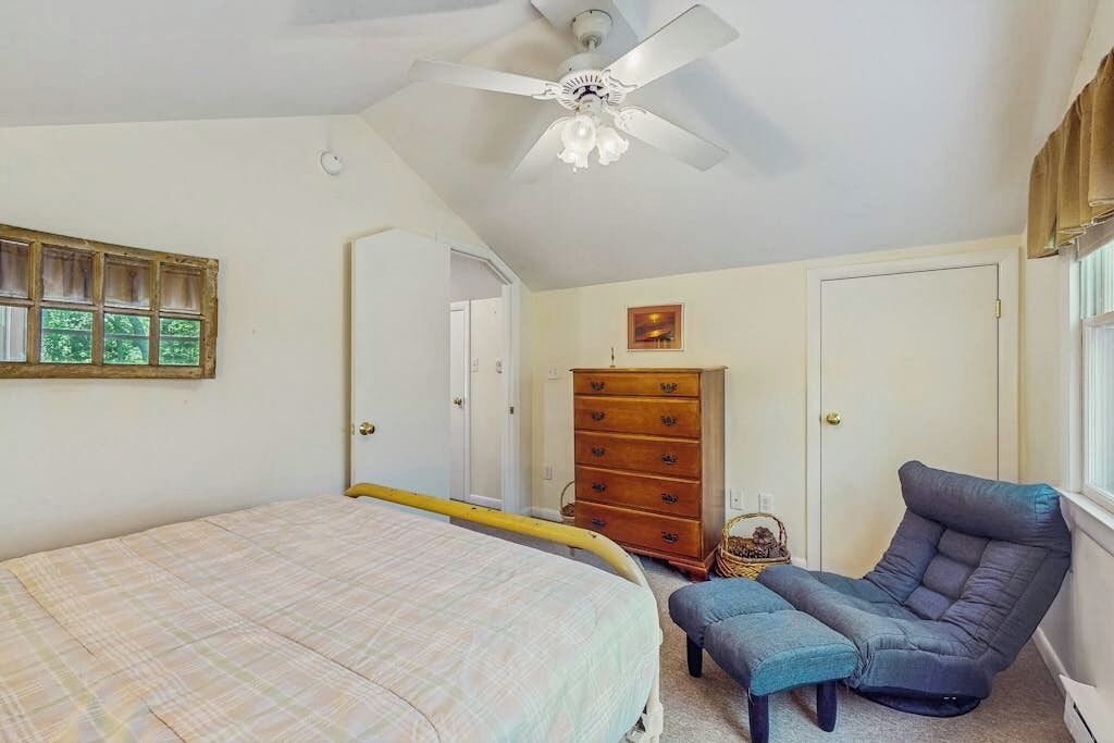 A bedroom with a bed, a chair, a dresser, and a ceiling fan.