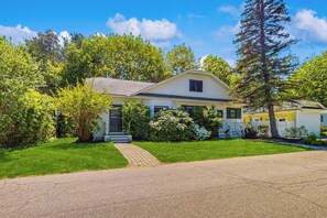 A two-story house with a front porch, a driveway, and a well-maintained lawn. - Dog-friendly home with full kitchen, private W/D, & outdoor firepit (Ogunquit)