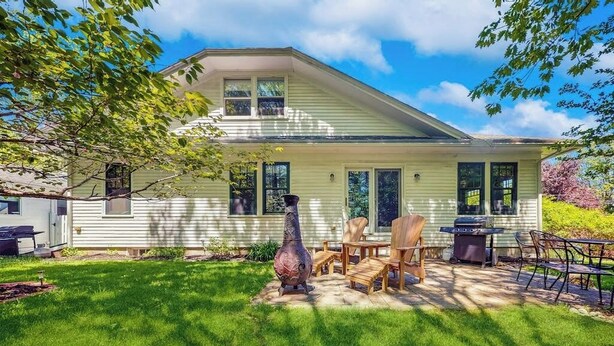 Ein Haus mit überdachter Terrasse, Gartenmöbeln und einer großen Zierurne.
