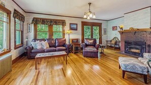Ein gemütliches Wohnzimmer mit Kamin, Ledermöbeln und großen Fenstern.