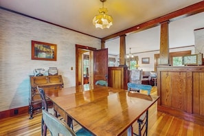 A dining area with a wooden table, chairs, a vintage radio, and a large window. - Dog-friendly home with full kitchen, private W/D, & outdoor firepit (Ogunquit)